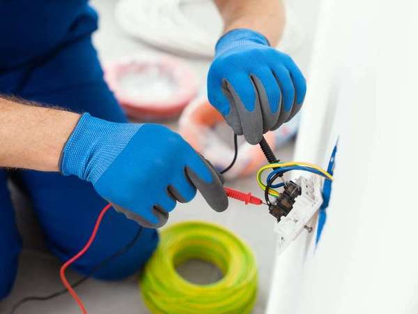 Electrician testing a faulty wall outlet with a meter
